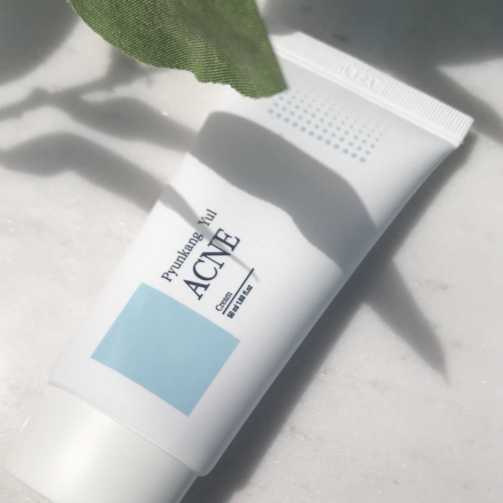 En tub Pyunkang Yul acne cream 50ml för naturlig exfoliering på ett marmorbord.